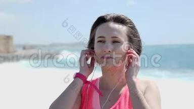 年轻的高加索女人在海滩上戴着耳机。 <strong>大风大</strong>浪.. 背景上的城堡